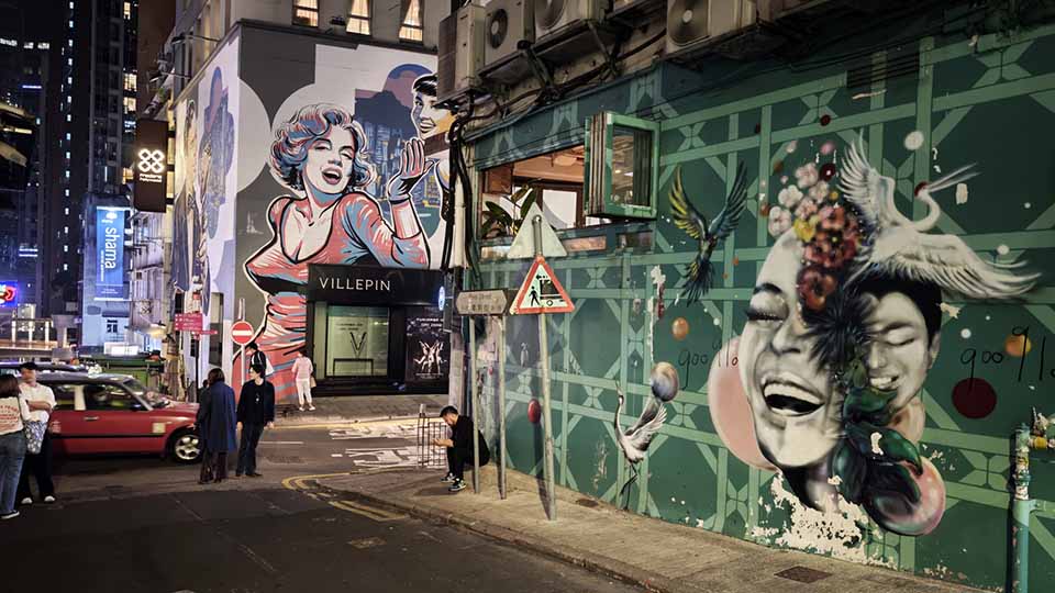 People on a street surrounded by murals in Soho, a popular nightlife area in Hong Kong