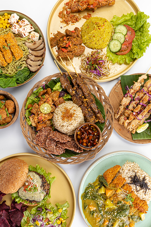 Several plates displaying food produced by Burgreens, including a veggie burger, veggie skewers, rice and salad