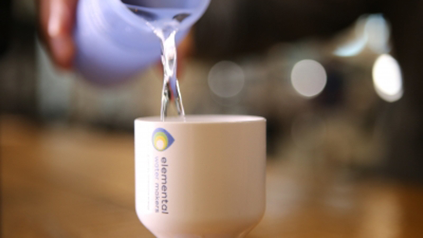 Someone pouring fresh water in an Elemental Water Makers cup