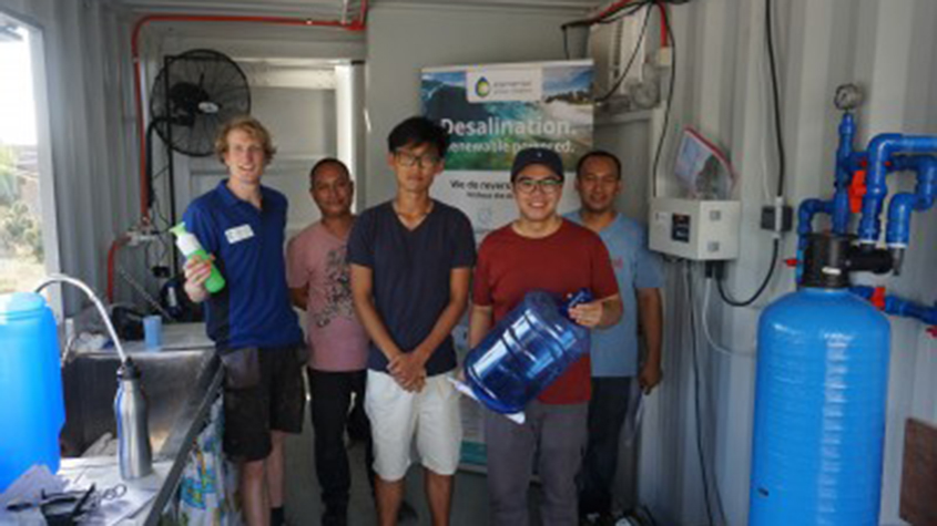 People filling in a water bottle with fresh water inside an Elemental Water Makers solar desalination plant