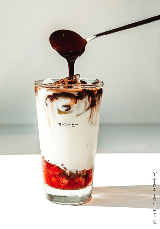 Photo shows one of Coffee ザ・コーヒー's signature beverages with fruit cream and coffee being poured n top from a spoon.