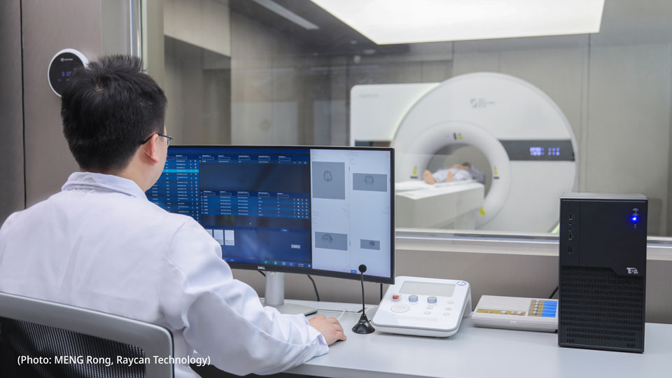 Photo of a man in a white hospital coat operating a PET-CT scan