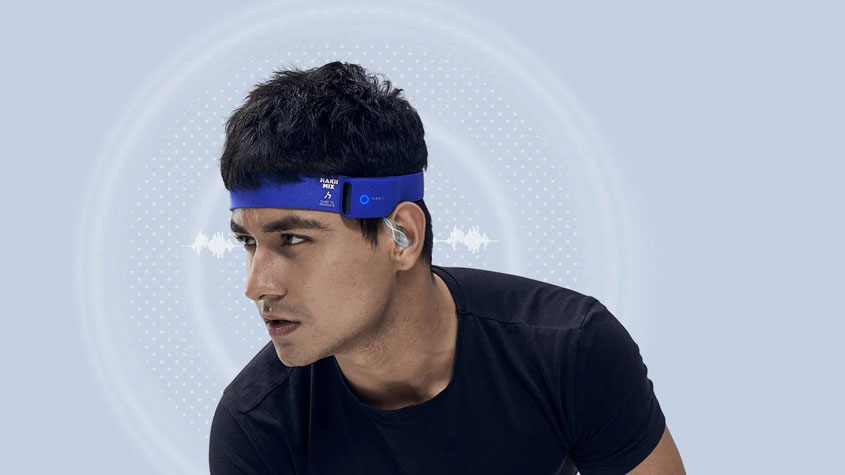图为一名男子戴着蓝色智能穿戴耳机打篮球
