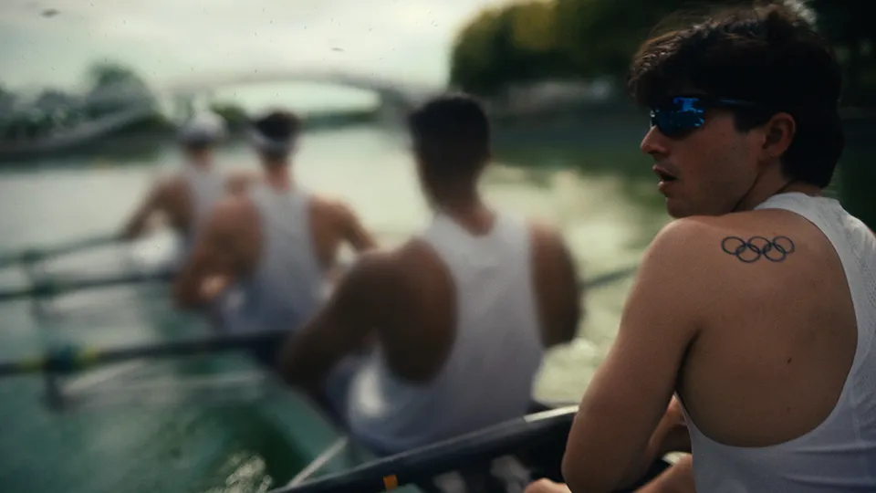 An Olympic rowing squad with athlete displaying the Olympic Rings as a tattoo on his shoulder