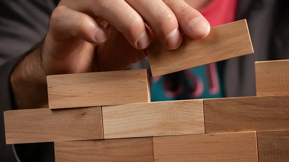 Hand building a small wall with wooden blocks