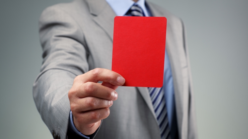 Un empresario mostrando una tarjeta roja, una representación conceptual del arbitraje en materia de propiedad intelectual en el mundo del deporte.